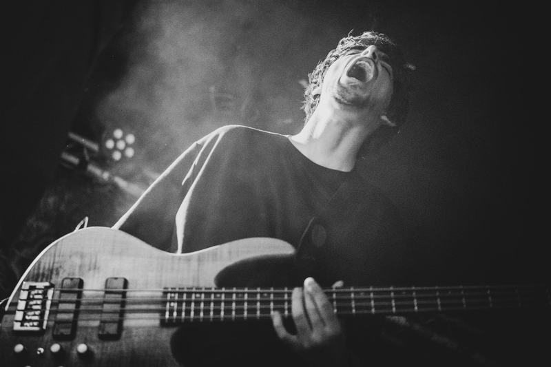 Bassist van Cold Grip schreeuwt met het hoofd achterover, zwart-wit