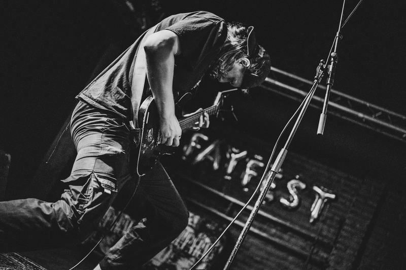 Gitarist van Serpenthead voor het FayFest-spandoek, zwart-wit